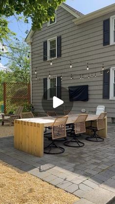 an outdoor patio with table and chairs in front of a house