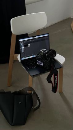 a laptop computer sitting on top of a wooden table next to a camera and bag