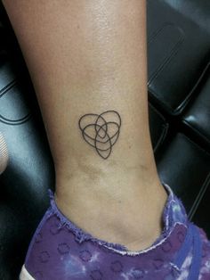 a woman's foot with a tattoo on the ankle and an intertwined heart