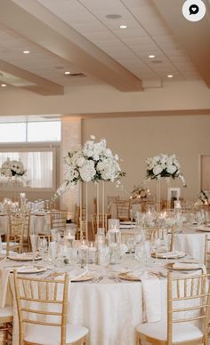 the tables are set up with white flowers and gold chairs for an elegant wedding reception