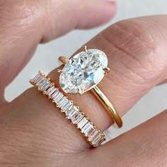 a woman's hand holding a ring with a diamond and baguette band