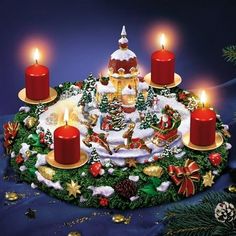 a christmas cake with lit candles on it and decorations around the edges, in front of a blue background