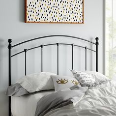 a bed with white sheets and black headboard in front of a painting on the wall