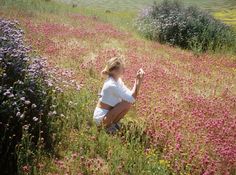 a woman kneeling down in a field of flowers