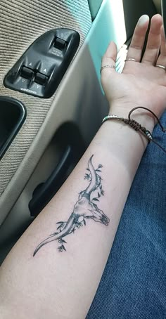 a woman's arm with a lizard tattoo on it, sitting in a car