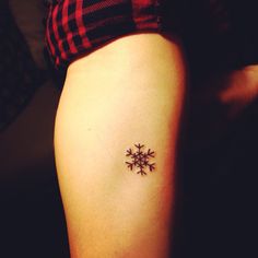 a small snowflake tattoo on the right side of the thigh, with black dots