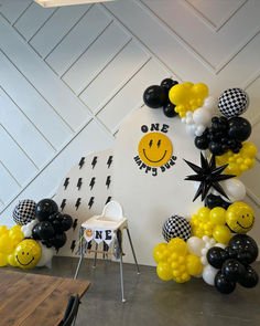 a balloon arch with smiley face balloons and black and white checkerboard decorations on the wall