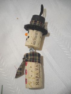 two wine cork snowmen with hats and scarves hanging from the top of each other