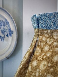 a blue and white vase sitting on top of a table next to a wall plate