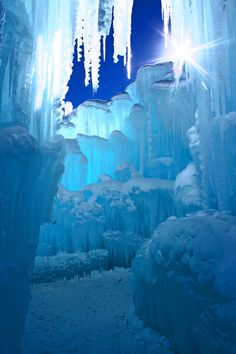 an ice cave with icicles hanging from it's ceiling and lights shining on the walls