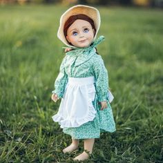 a doll is standing in the grass wearing a green dress and hat