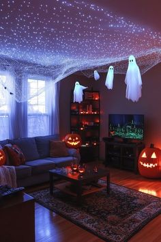 a living room decorated for halloween with pumpkins and ghost heads hanging from the ceiling