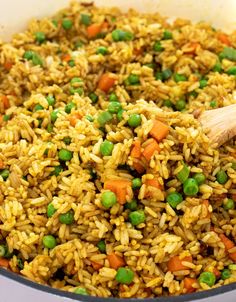 a pot filled with rice and peas next to a wooden spoon