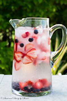 a pitcher filled with ice and strawberries on top of a table