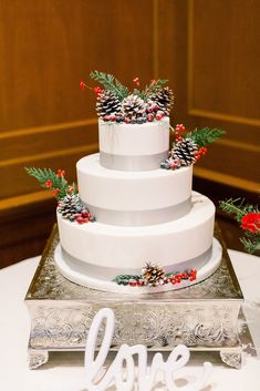 a wedding cake with pine cones and berries on top