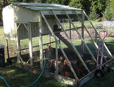 a chicken coop with chickens in it and a hose attached to the roof, on grass