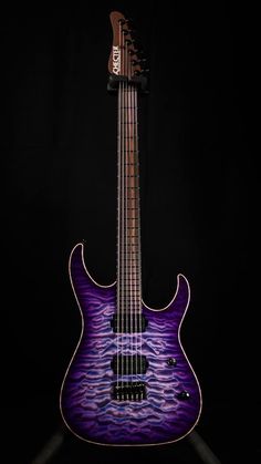 a purple electric guitar sitting on top of a black background with its neck and frets