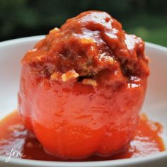 a tomato stuffed with meat and sauce in a white bowl