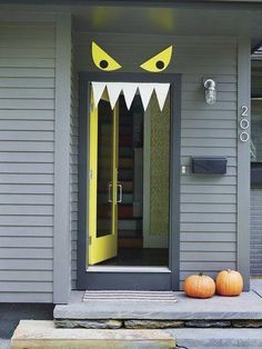 two pumpkins sitting on the front porch of a house with monster's teeth painted on it