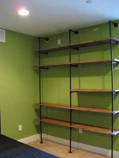 an empty room with green walls and shelving unit in the corner on the floor