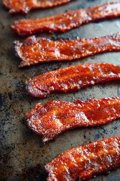 bacon strips are lined up on a baking sheet