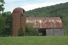 an old rusted barn sits in the middle of a field