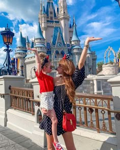 two girls in front of a castle pointing at the sky with their hands up and one girl holding onto her shoulder