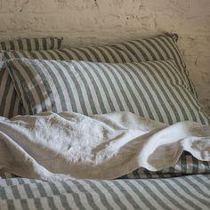 an unmade bed with striped sheets and pillows