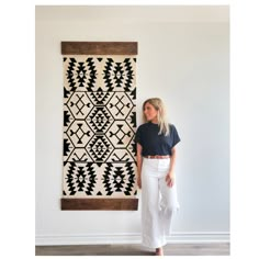 a woman standing in front of a wall hanging