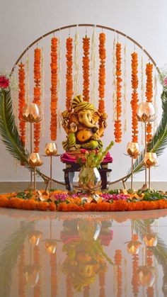 an idol sitting on top of a table surrounded by flowers and garlands with lights hanging from the ceiling