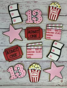 some decorated cookies are sitting on a white table with pink and red decorations in the shape of popcorn boxes