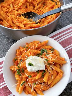 a white plate topped with pasta next to a pan filled with cheese and other food