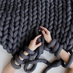 a woman's hands are holding onto a large gray rope that is connected to the ground