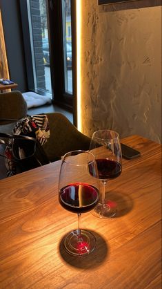 two glasses of wine sitting on top of a wooden table