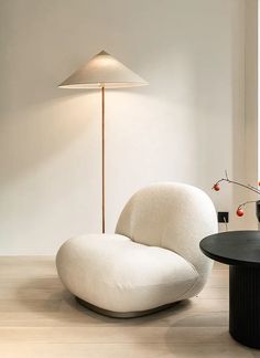 a white chair sitting next to a table with a lamp on it's side