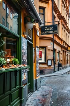 an alleyway with tables and chairs on the sidewalk in front of some tall buildings