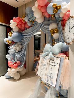 an arch made out of balloons with a clock on the wall in front of it