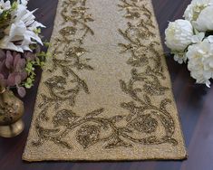 a gold table runner with flowers and vases in the background