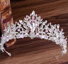 a tiara with pink and white flowers on it sitting next to an old book