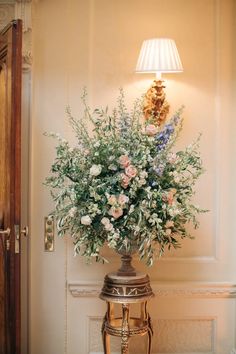 a vase filled with lots of flowers sitting on top of a table next to a lamp