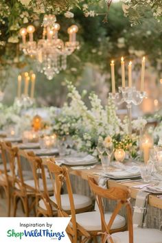 a long table with white flowers and candles is set up for an outdoor wedding reception