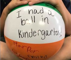 a person holding a large ball with writing on it and saying i had a ball in kindergartia