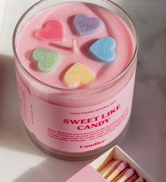 a pink candle with heart shaped candies in it