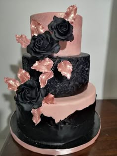 a three tiered cake with black and pink frosting flowers on the bottom layer