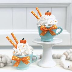 two cups filled with whipped cream and pumpkin decorations