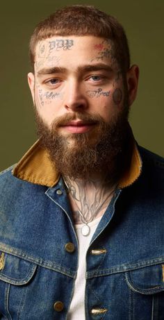 a bearded man with tattoos on his face and chest is looking at the camera while wearing a denim jacket