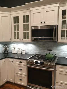 a kitchen with white cabinets and black counter tops