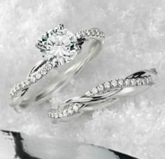 two white gold wedding rings with diamonds in them on snow covered ground next to each other