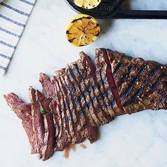 a steak on a marble counter top next to other food items and utensils