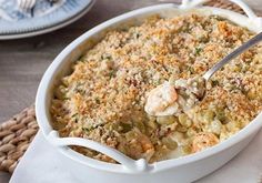 a white casserole dish filled with shrimp and vegetables on top of a table